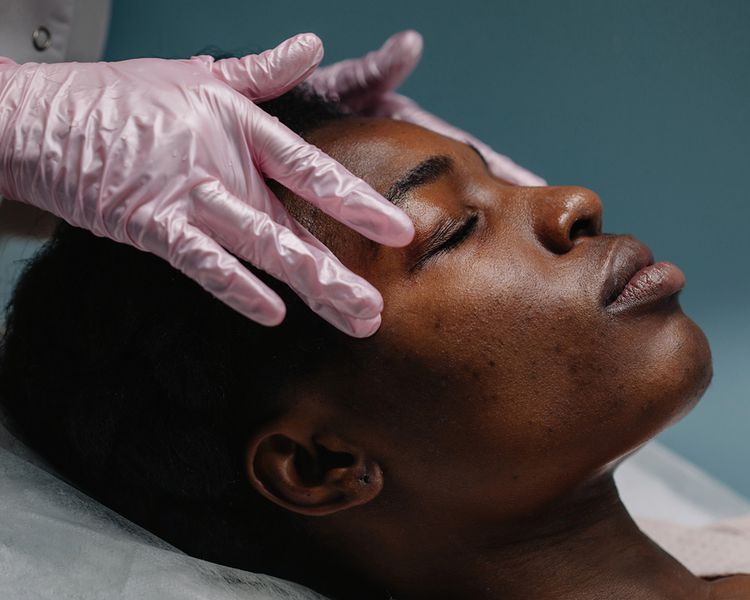 Uma mulher recebe massagem facial de um profissional.